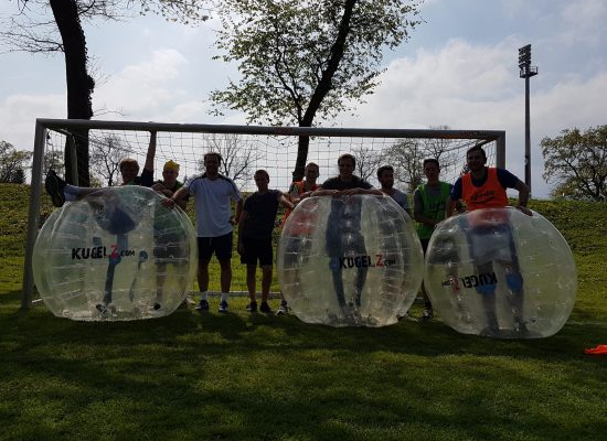 Männer eines Junggesellenabschieds stehen neben Bubble Soccer Bällen
