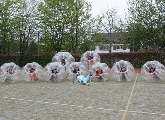 Männer eines Polterabends liegen in Bubble Soccer Bällen