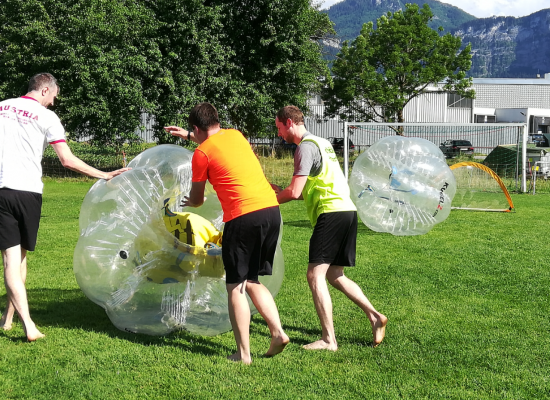 Männer rollen Bräutigam am Junggesellenabschied in Bubble Soccer Ball